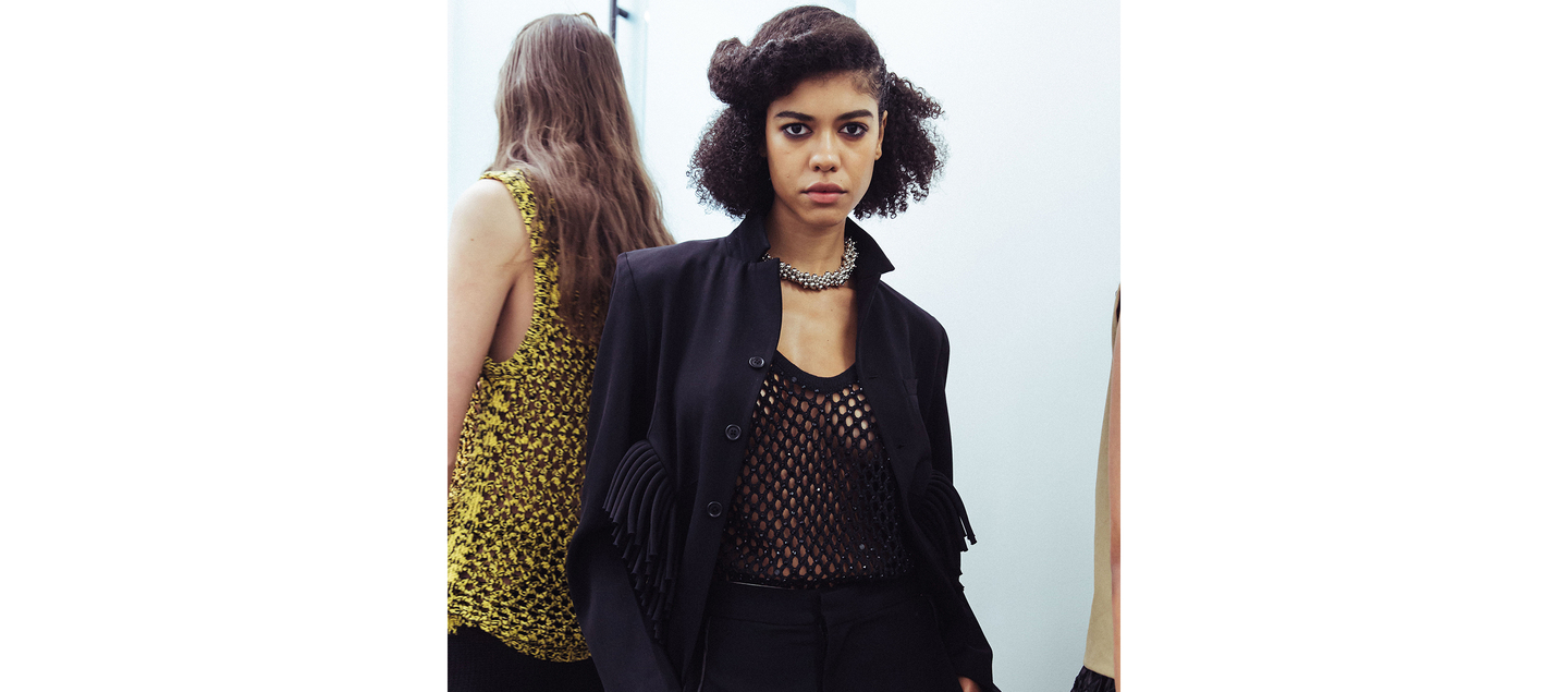 Close-up of a model with a textured hairdo and black fringed outfit at NYFW F/W 2024.